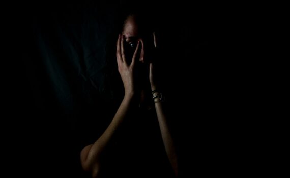 woman holding her face in dark room