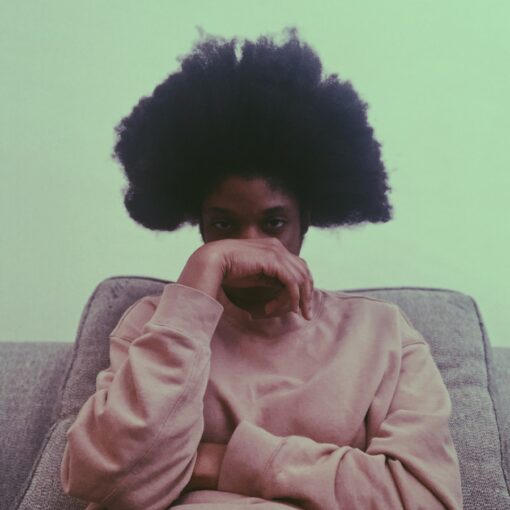 woman in pink sweater sitting on gray couch