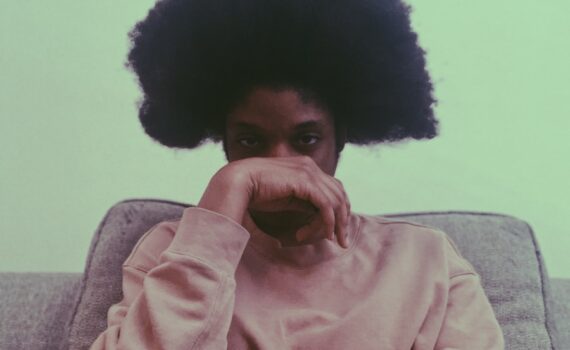 woman in pink sweater sitting on gray couch