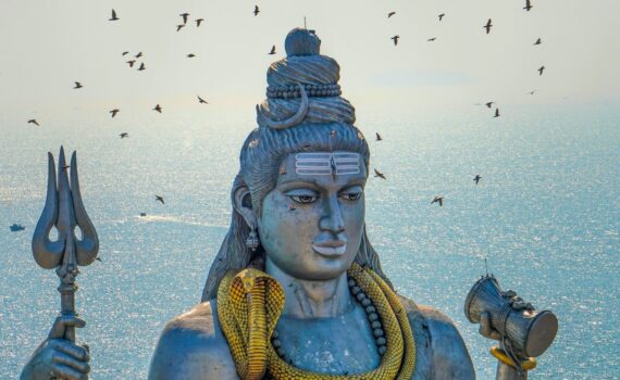 a statue of a hindu god with birds in the background